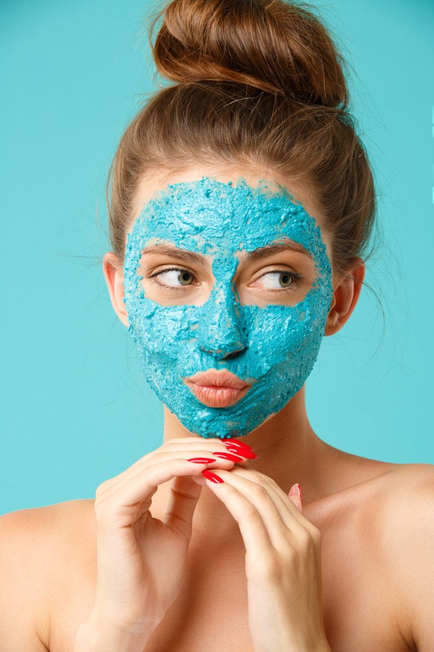 Beauty treatment - woman applying clay face scrub mask