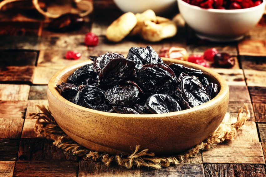 Dried sweet prunes or dark plums in bowl
