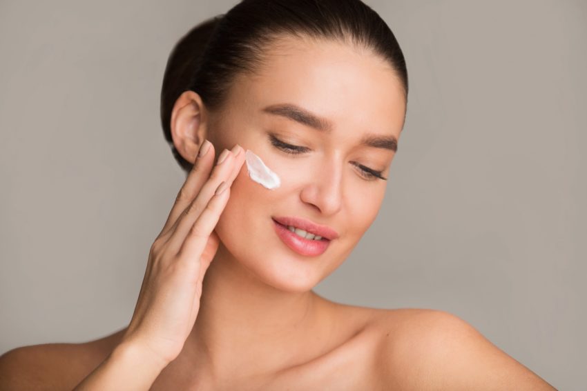 Portrait of woman applying moisturizer cream on face